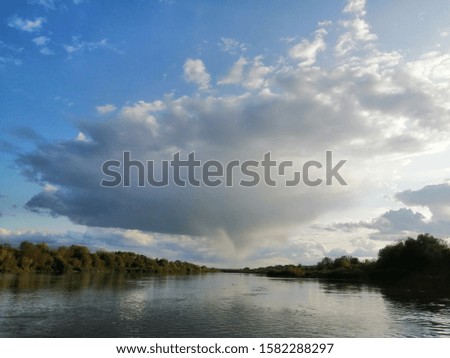 a big storm cloud and the sun over the river