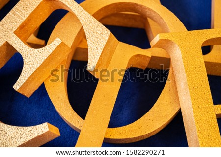 letters cut out of polystyrene with gold color on a blue background. blank for decoration, logo making