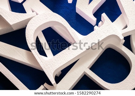 white letters cut out of foam without painting on a blue background. blank for decoration, logo making