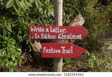 "Write a letter to Father Christmas" and "Festive Trail" Christmas Signs Attached to a Wooden Post in a Garden in Rural Cornwall