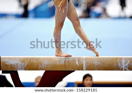 Legs of a gymnast are seen during an exercise on the balance beam apparatus