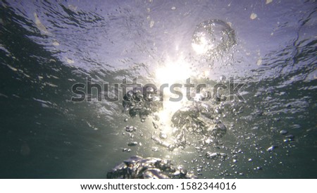 Underwater oxygen bubbles as seen from scuba diver reaching the surface