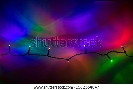 Christmas lights on a wire reflecting colorful on a wall