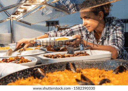 Stock photo of a girl taking food from a restaurant counter. Lifestyle