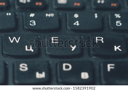 Closeup black keyboard with Ukrainian and English alphabet layout.