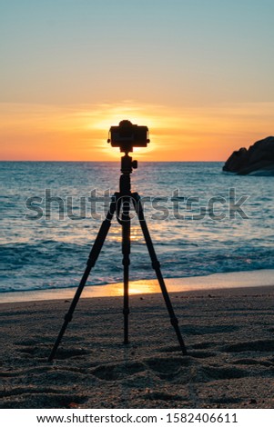 Camera standing on a tripod on the beach against the background of dawn