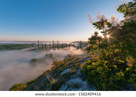 Sunrise over hills in fog, scullia vulgaris on spring landscape. Blue morning sky and sun