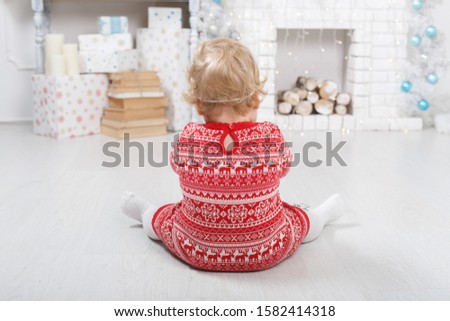 portrait a little girl  in a red dress near a  brick fireplace in christmas decorated home. christmas  Holidays indoors with toys and gift box, childhood concept.