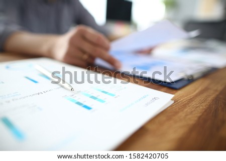Close up of male employee read paper handout material during office meeting, man analyzing paperwork report at briefing. Royalty-Free Stock Photo #1582420705