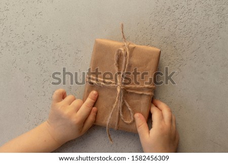 Gift box in a child hands on a grey background