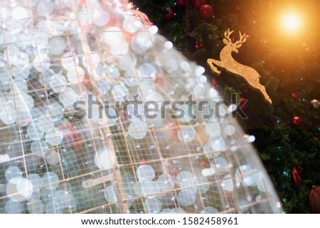 Golden Reindeer Christmas decorations on the Christmas tree with the foreground Christmas lighting globe bokeh and warm tone light ray shine from the right top corner.