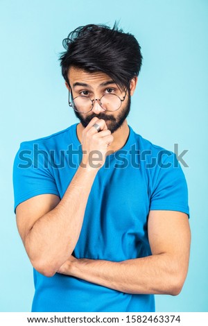 Emotional portrait of a handsome Hindu man in a blue T-shirt on a bright blue background