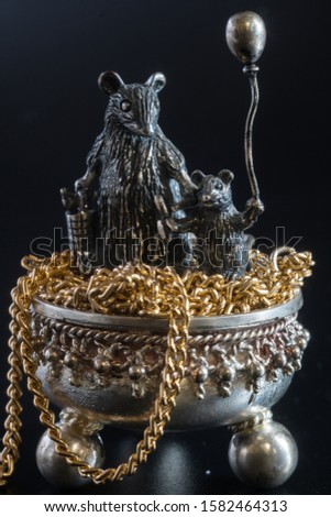 Composition from metal figures from gold and silver. Mom rat and baby on a pot of chains. Concept of the year 2020 on the eastern calendar. Symbol of wealth and family well-being Black background