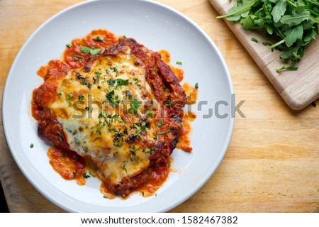Chicken Parmesan or parmigiana. Italian comfort dish. Chicken breast covered in breadcrumbs fried, topped with marinara sauce, melted mozzarella, parmigiana and provolone cheeses and Italian parsley.  Royalty-Free Stock Photo #1582467382