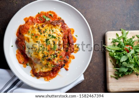 Chicken Parmesan or parmigiana. Italian comfort dish. Chicken breast covered in breadcrumbs fried, topped with marinara sauce, melted mozzarella, parmigiana and provolone cheeses and Italian parsley.  Royalty-Free Stock Photo #1582467394