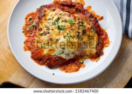 Chicken Parmesan or parmigiana. Italian comfort dish. Chicken breast covered in breadcrumbs fried, topped with marinara sauce, melted mozzarella, parmigiana and provolone cheeses and Italian parsley.  Royalty-Free Stock Photo #1582467400