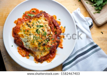 Chicken Parmesan or parmigiana. Italian comfort dish. Chicken breast covered in breadcrumbs fried, topped with marinara sauce, melted mozzarella, parmigiana and provolone cheeses and Italian parsley.. Royalty-Free Stock Photo #1582467403