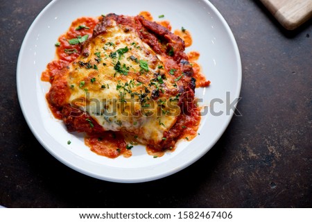 Chicken Parmesan or parmigiana. Italian comfort dish. Chicken breast covered in breadcrumbs fried, topped with marinara sauce, melted mozzarella, parmigiana and provolone cheeses and Italian parsley.  Royalty-Free Stock Photo #1582467406