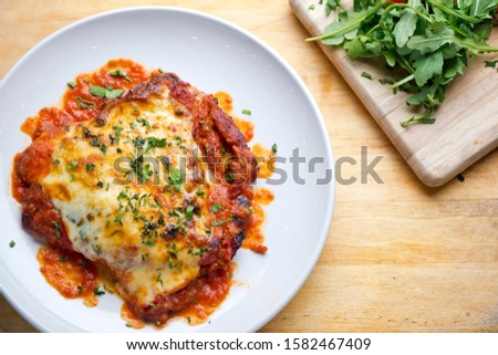 Chicken parmigiana Traditional Italian comfort dish. Chicken breast covered in breadcrumbs lightly fried, topped with homemade marinara, melted mozzarella, parmigiana provolone and Italian parsley.  Royalty-Free Stock Photo #1582467409