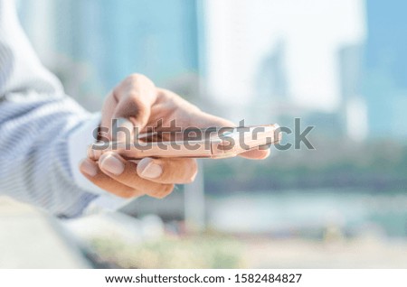 close up business man using hand typing smartphones and touch screen working search with app devices outdoor in city with sunrise and building background. 5G technology connecting the world.