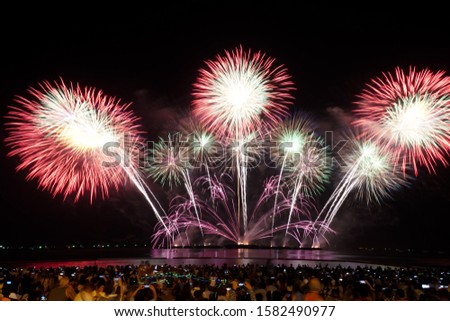 Many people are excited and have fun watching the fireworks show and using a smartphone to take pictures.