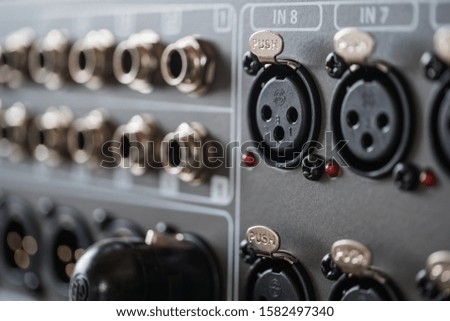 A closeup selective focus shot of professional studio audio recording equipment with a microphone and musical instruments input jacks