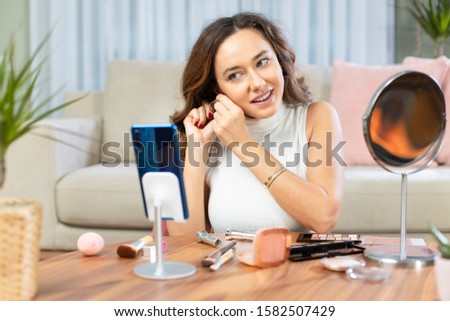 Famous blogger. Cheerful female vlogger recording with smart phone and showing cosmetics products while recording video and giving advices for her beauty blog.
