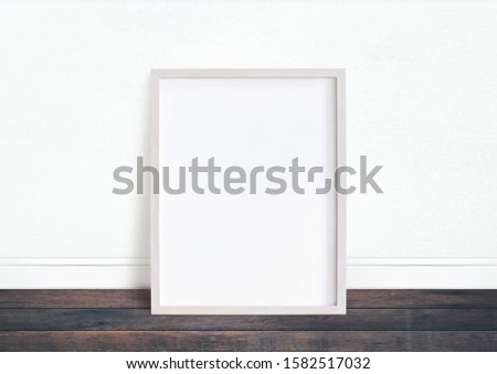 Empty white frame image mockup. White wall and desk floor.