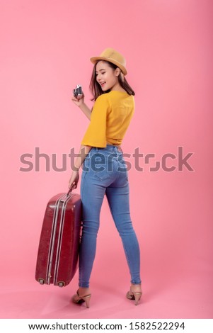 Traveler tourist asian woman in summer with suitcase and camera on pink background. Vertical image.