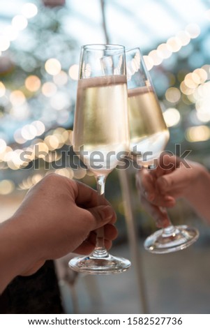 Champagne glass clink and cheers in fronts of festive background light bokeh Royalty-Free Stock Photo #1582527736
