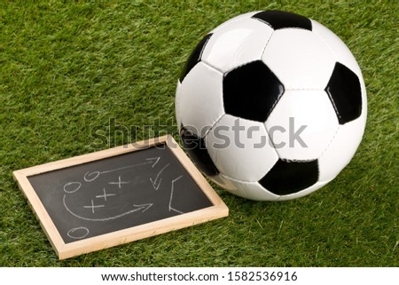 Soccer sports ball with game strategy drawing blackboard on grass background - selective focus