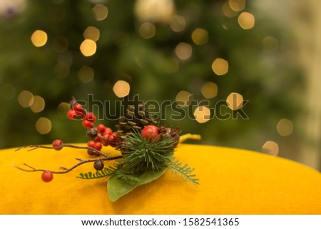 Christmas decorative spruce branch with pine cone and berries on a background of lights