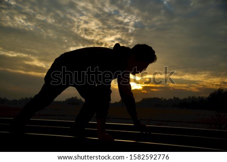 Man bending down on the railway tracks in the dark afternoon