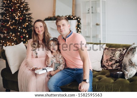Smiling mother giving gift box to cute little daughter during Christmas event dinner feeling love