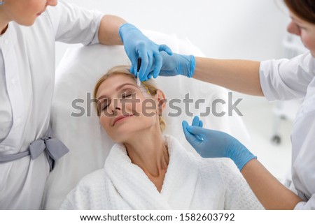 Specialists preparing a woman for lifting procedure stock photo