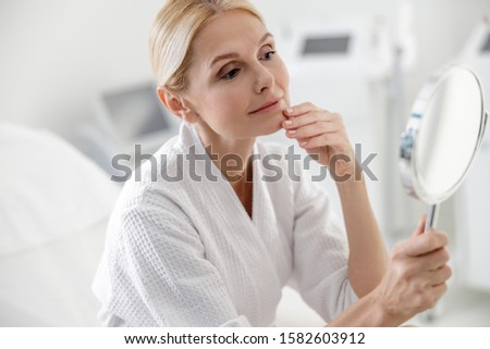Beautiful adult woman using mirror in spa center stock photo