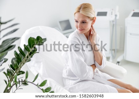 Waist up of smiling lady sitting on the couch in the spa center stock photo