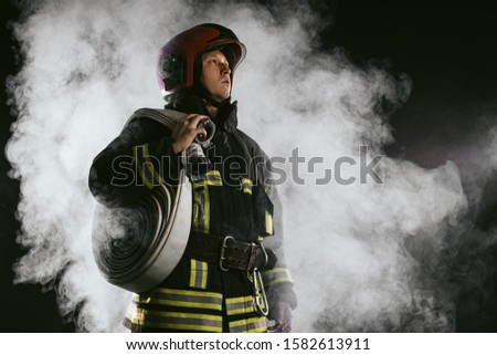 brave man fire fighter extinguishing fire, work at fire station and doing his work wearing protective uniform