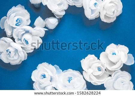 white flower buds on a blue background top view.  color of the year 2020 pantone classic blue