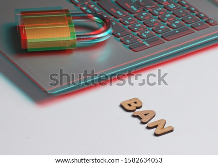 Ban account. Lock on laptop keyboard on white background with the word ban of wooden letters. Glitch effect