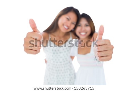Two pretty young women showing thumbs up on white background