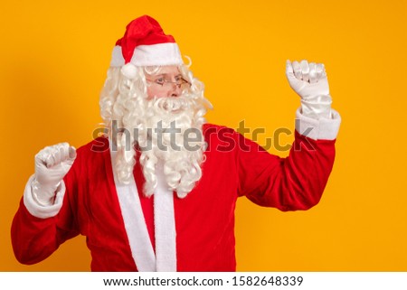 Male actor in a costume of Santa Claus dancing, gesturing and posing