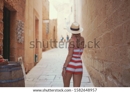 Young positive woman walking in hat on Mediterranean street