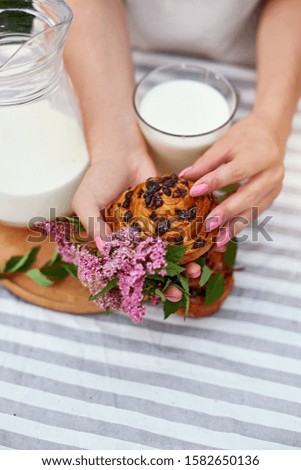 girl holding a sweet bun. glass of milk on the table. white and green background. concept composition breakfast 