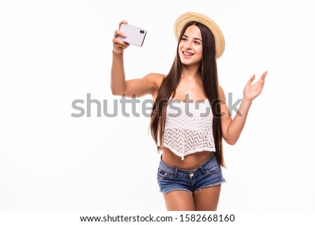 Smiling young girl making selfie photo while waving palm isolated on a white background