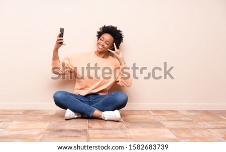 African american woman sitting on the floor making a selfie