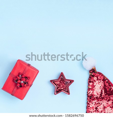 New Year and Christmas composition. Frame from red balls, red star, gift boxes, Santa's hat and sparkles on pastel blue paper background. Top view, flat lay, copy space, instagram format