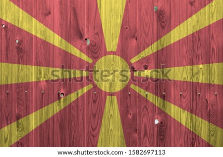 Macedonia flag depicted in bright paint colors on old wooden wall. Textured banner on rough background