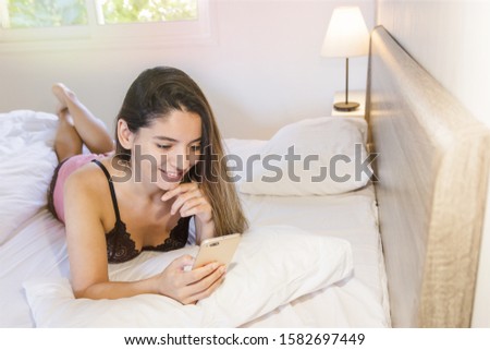 attractive caucasian woman lying on bed. pretty girl using cellphone and resting