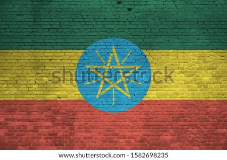 Ethiopia flag depicted in paint colors on old brick wall. Textured banner on big brick wall masonry background